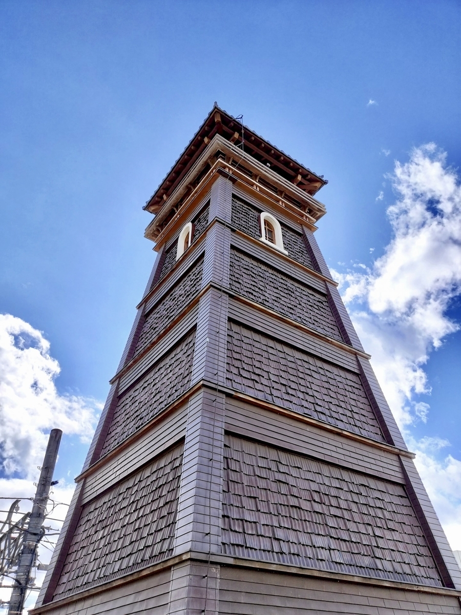 青空を背景に時の鐘の鐘楼を真下から見上げた外観