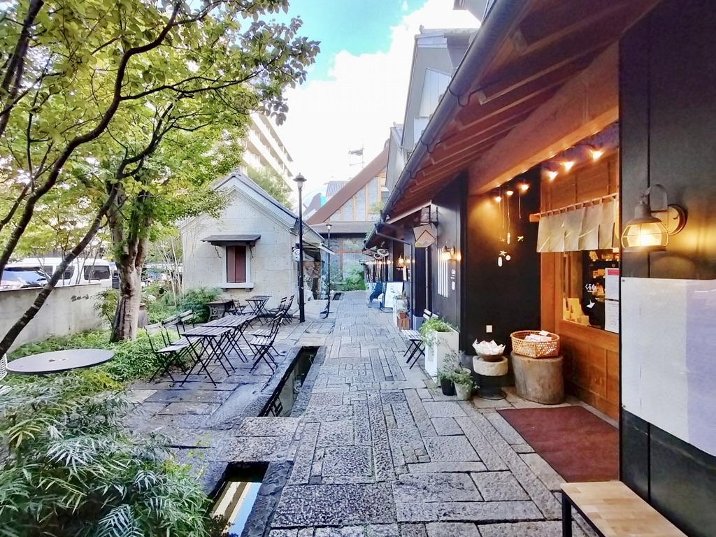 石畳の通りに用水路が流れテーブル席が並ぶ甲州夢小路の中庭