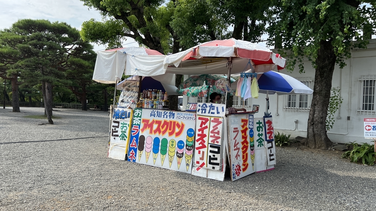 รถเข็นขายของเคลื่อนที่「ไอศกรีม」ที่ตกแต่งด้วยป้ายสีสันสดใส มีร่มสีขาว