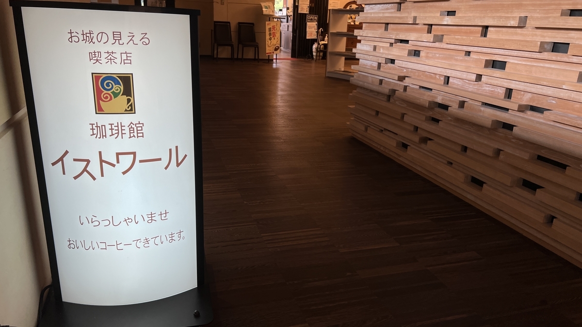 ป้ายทางเข้าคาเฟ่ 'Histoire' ที่มองเห็นปราสาทโคจิ ตกแต่งด้วยไม้และให้บรรยากาศอบอุ่น