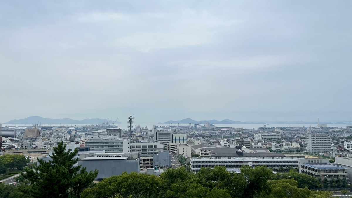 丸亀市街と遠くの山並みを望む眺望。曇り空でも広がりを感じる風景