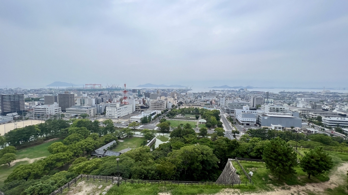 広がる街並みと曇り空の下に見える市内中心部。奥には山々も見える