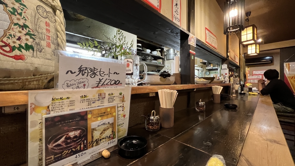 Asientos en la barra de Goya con menús y botellas de sake, ambiente acogedor