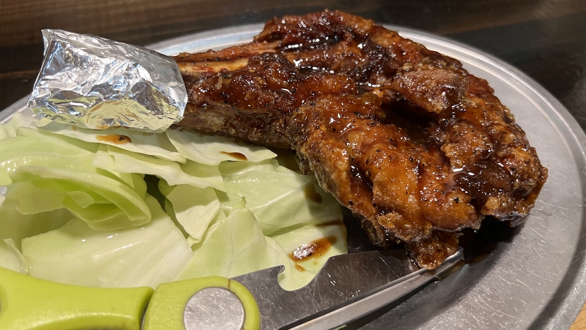 Pollo con hueso asado crujiente servido con repollo en un plato de metal