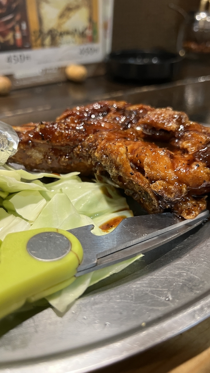 Primer plano del pollo con hueso acompañado de tijeras, uno de los platos estrella de Goya
