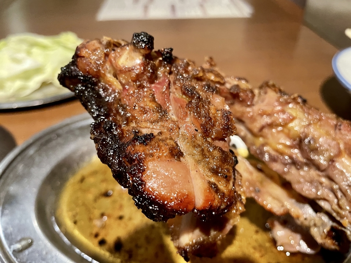 Close-up of honetsukidori being held up, with crispy skin and juices dripping from the meat