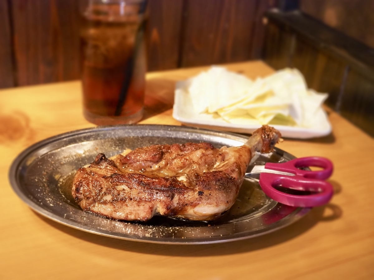 Honetsukidori served on an iron plate with cabbage and a drink in the background—Kagawa’s signature nighttime dish