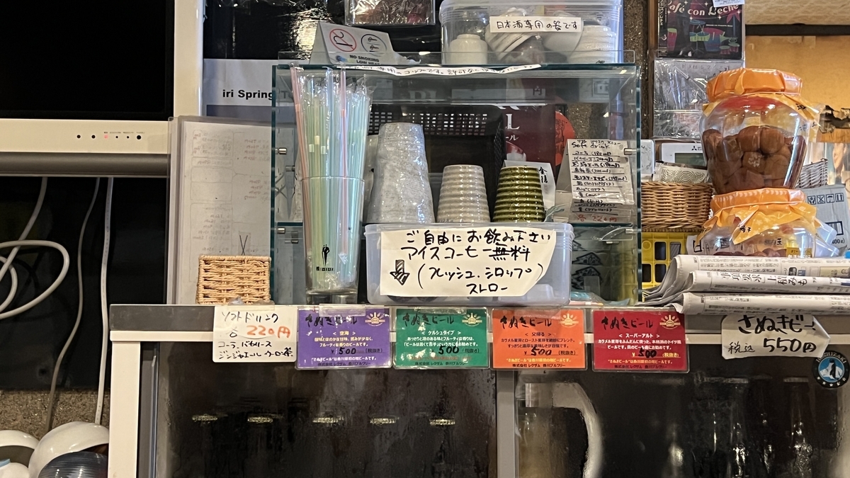 セルフサービスで提供されているアイスコーヒーと紙コップが置かれた冷蔵庫の上部