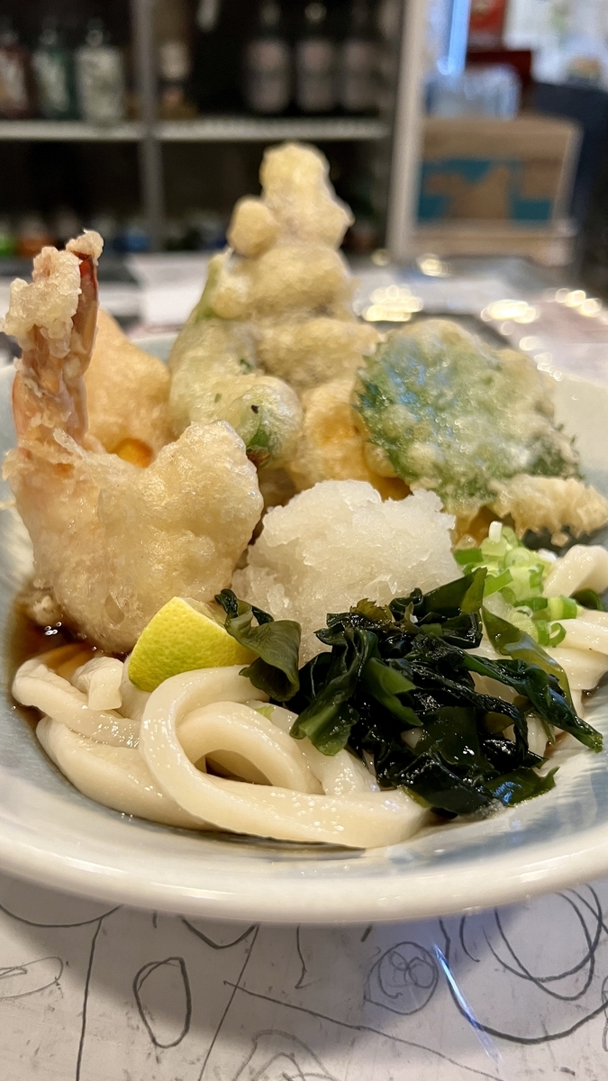 天ぷらぶっかけうどんの縦構図。揚げたての天ぷらとつややかな麺が盛られた一杯