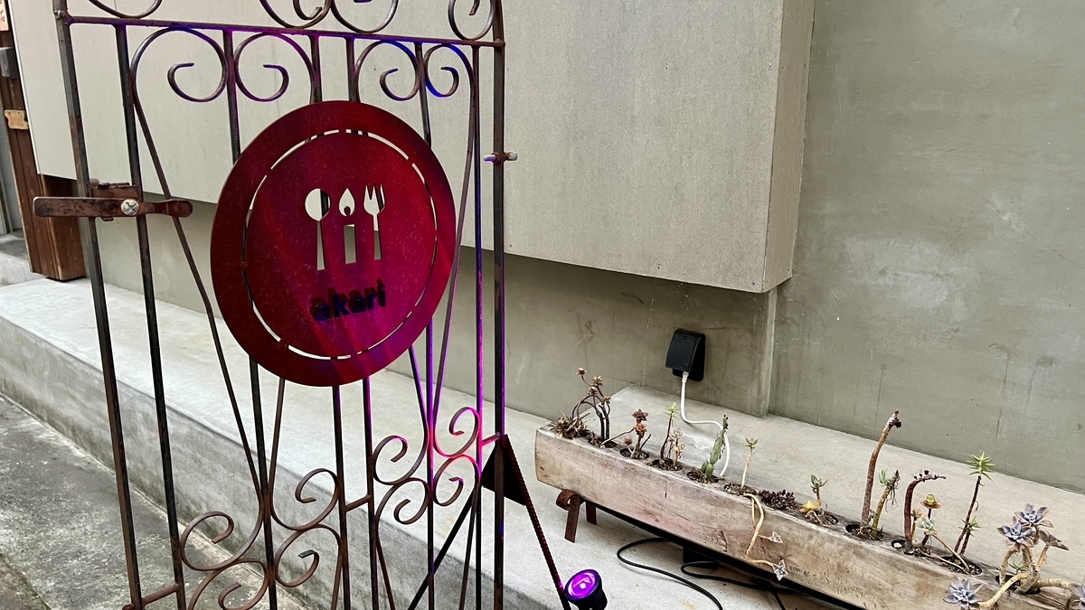 Red logo and gate-like sign with decorations in front of the restaurant