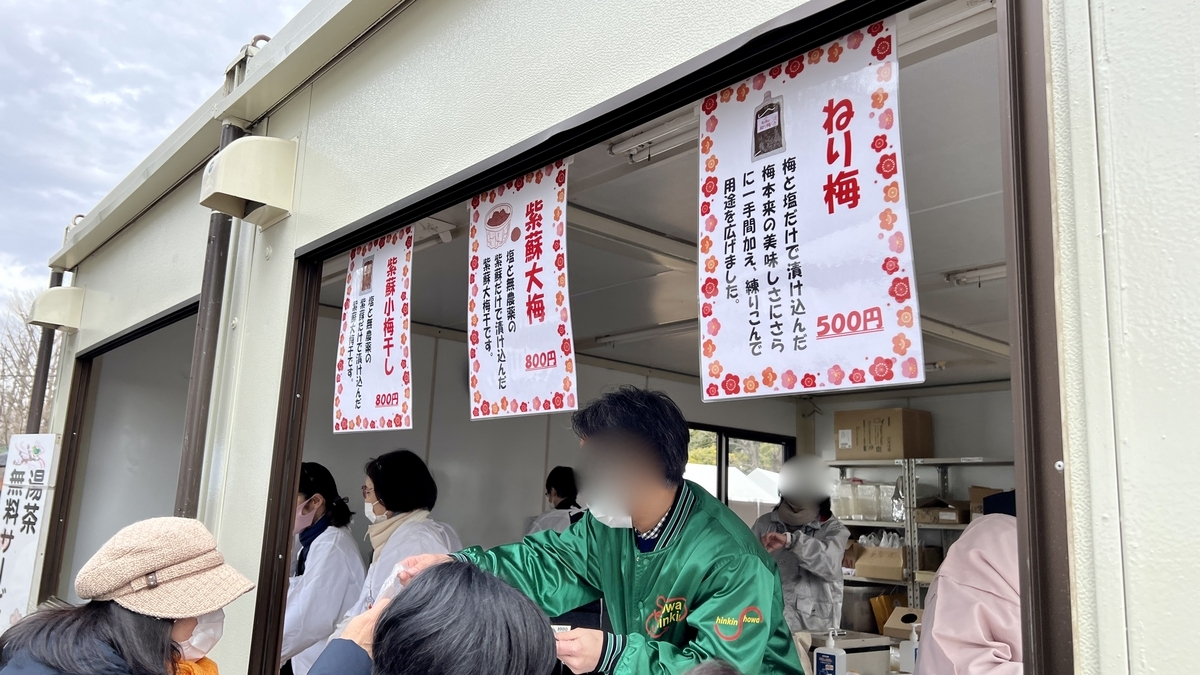 Staff in green coats selling plum jam at a food stall