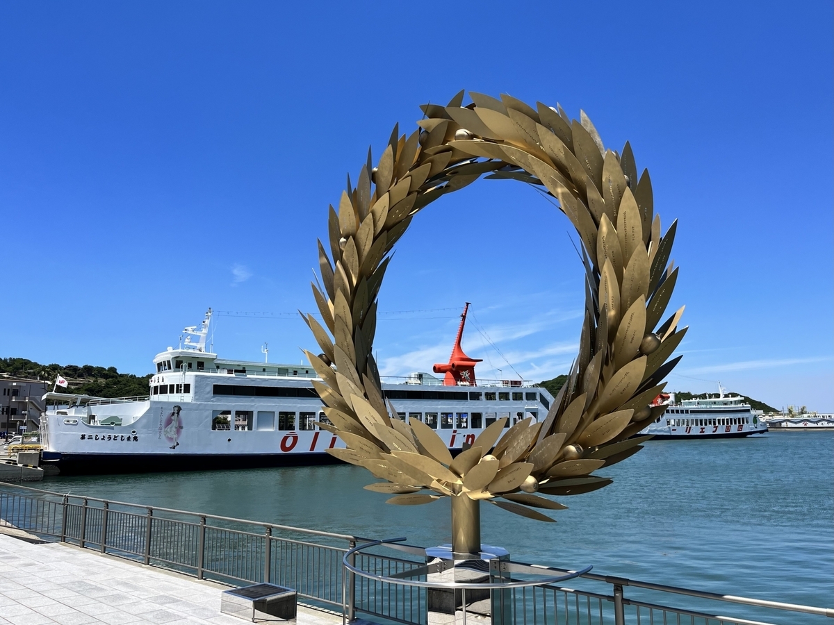 Tonosho Port’s iconic “Gift of the Sun” monument floating above the sea under a clear blue sky.