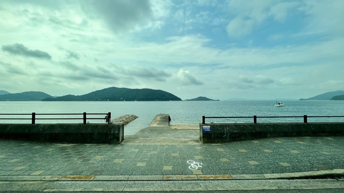 View of the Seto Inland Sea and a seaside bench from the bus window.