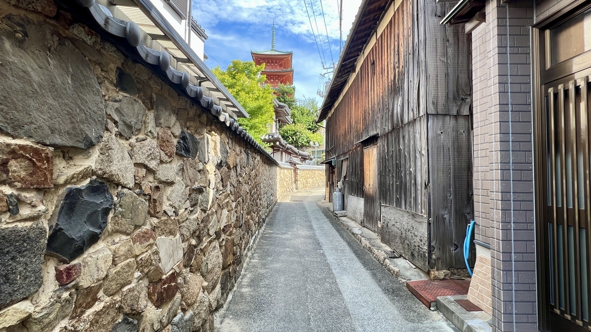 Alleyway flanked by stone and wooden walls leading to Saikōji Temple in the distance.