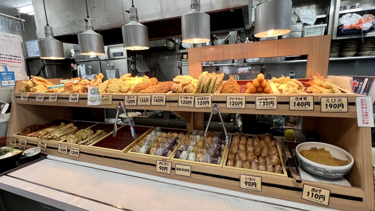 Área de toppings en Merikenya con gran variedad de tempura, onigiri y más