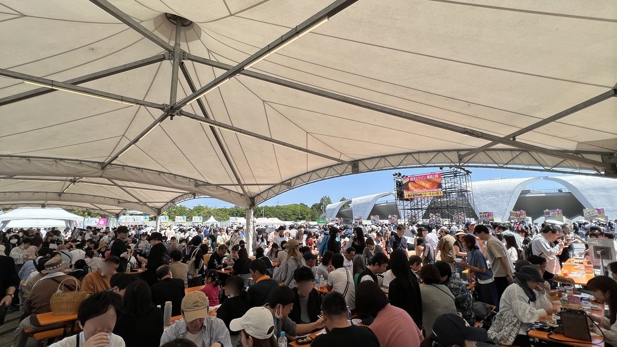Asistentes comiendo en mesas altas bajo una carpa en el Craft Gyoza Fes Tokio