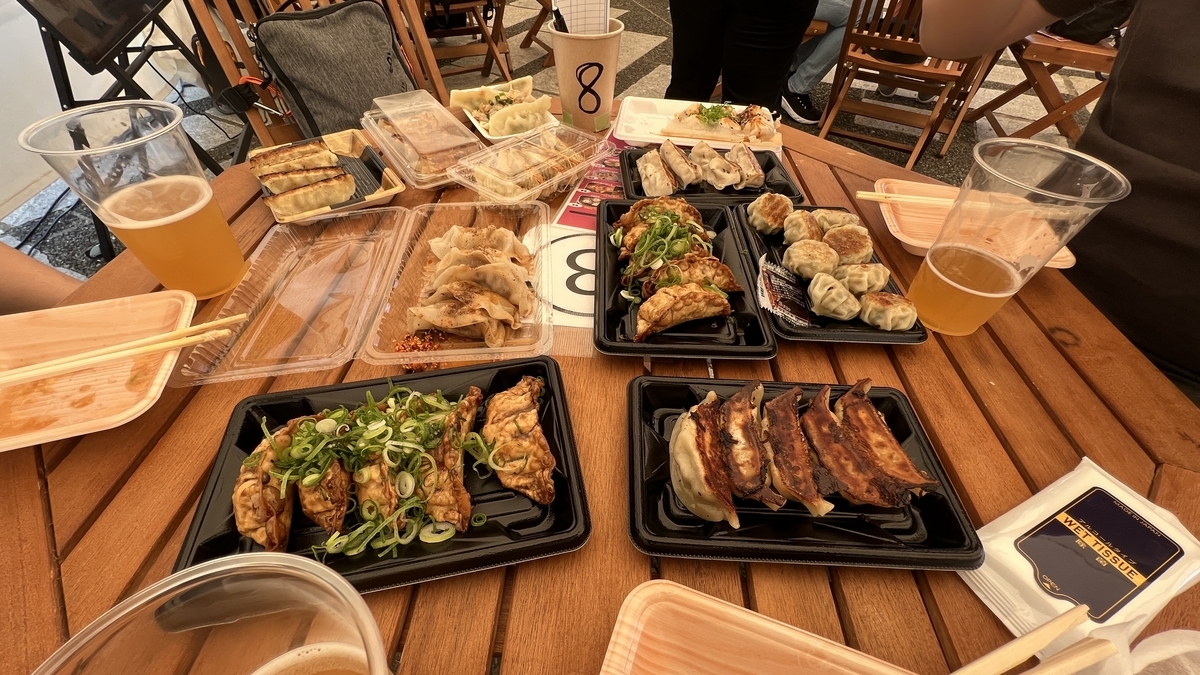 Mesa llena de gyozas y bebidas de diferentes puestos