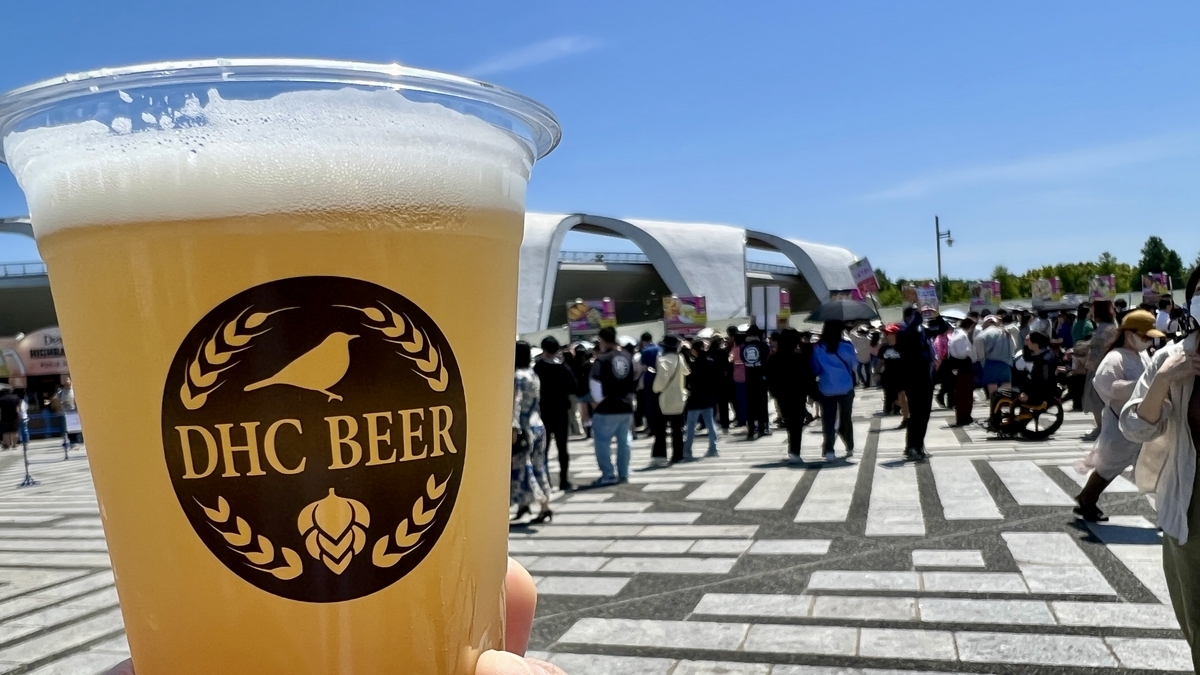 Visitante sosteniendo una cerveza DHC frente a la entrada del Craft Gyoza Fes Tokio