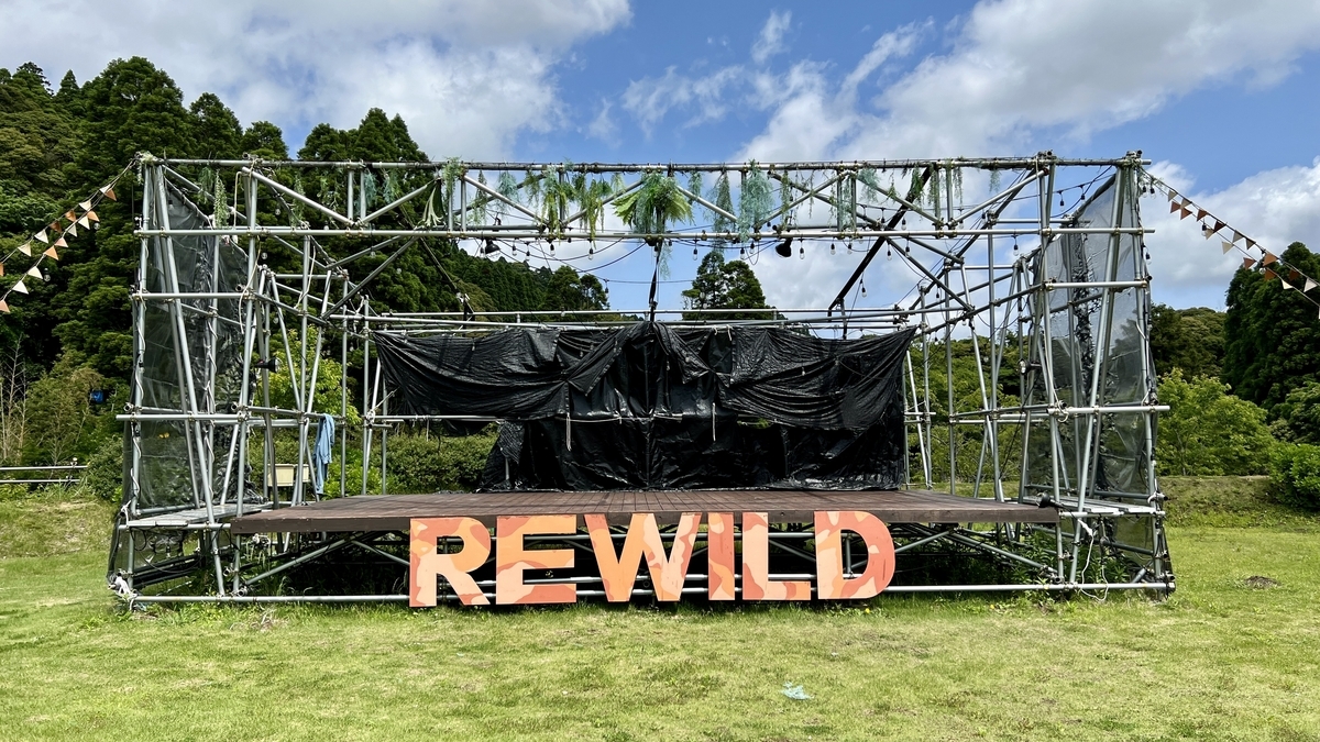 芝生の上に設置されたREWILDの文字が並ぶ大型ステージの全景