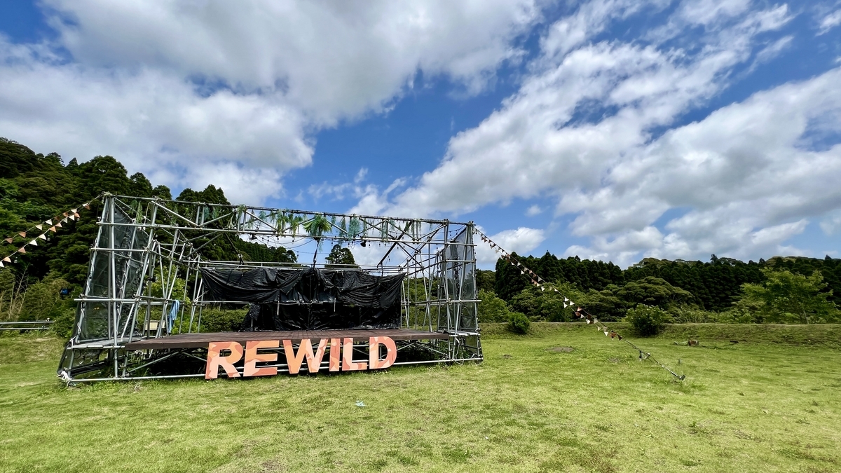 青空の下に立つ金属フレーム構造のREWILDステージの近景