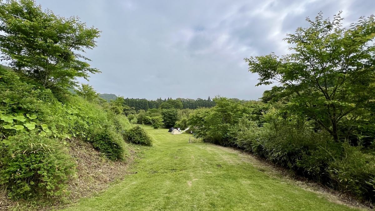 木々に囲まれた静かなファミリーエリアの芝生サイト入口の風景