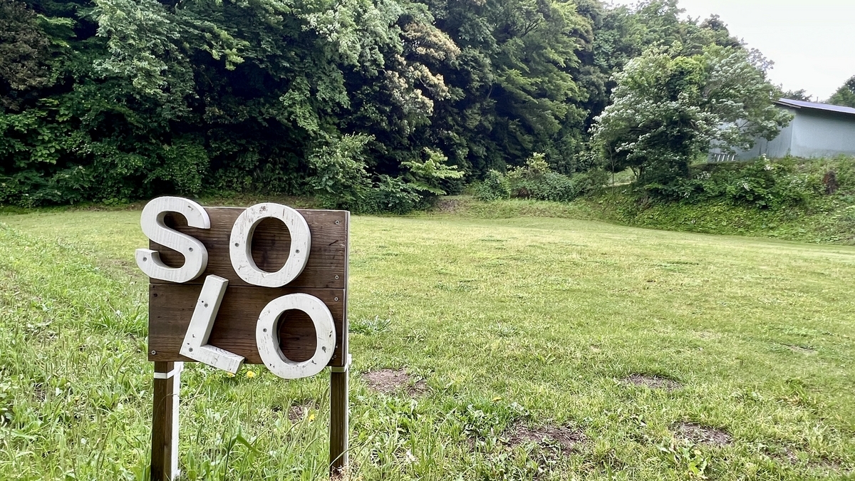 SOLOの木製サインが立つソロキャンプ専用エリアの芝生サイト