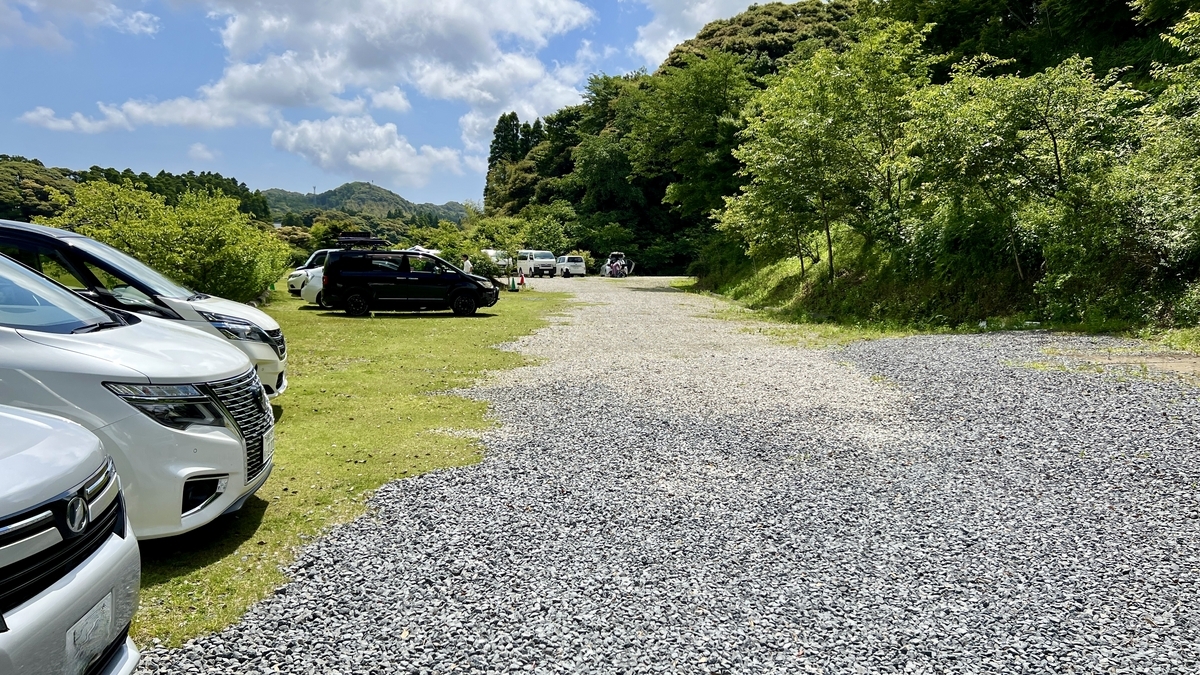 青空の下に並ぶ車と緑に囲まれたキャンプ場の駐車エリア
