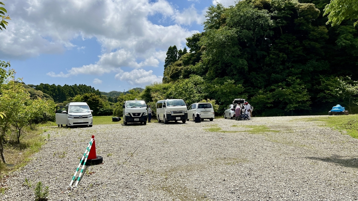 開放的な芝生サイト奥に隣接するキャンプ場の駐車場全景