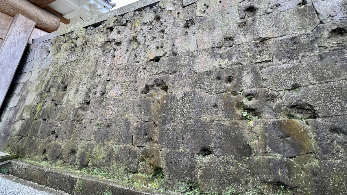 Stone-paved path beside the stone walls lined with rows of bullet holes