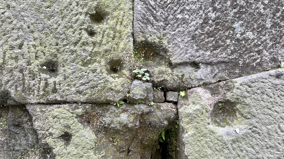 Close-up view of small bullet marks remaining on the surface of the stone wall