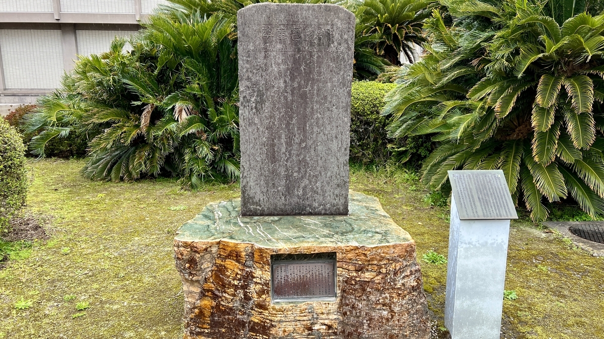 Shuuchin Houkohi monument and explanatory board surrounded by greenery near the Reimeikan