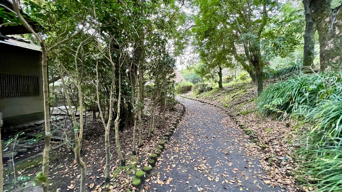 Quiet path surrounded by trees behind the Reimeikan leading to the garden area