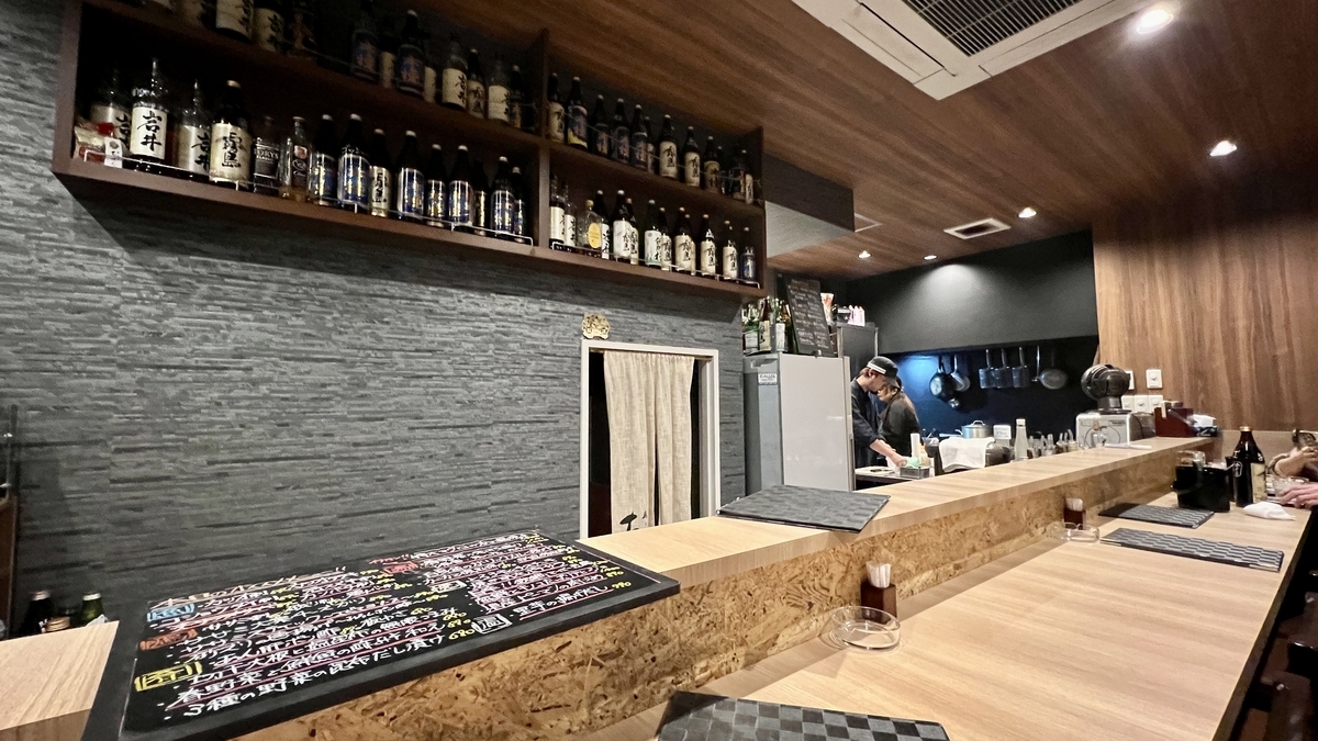 나무 카운터와 선반에 술이 진열된 차분한 실내 모습