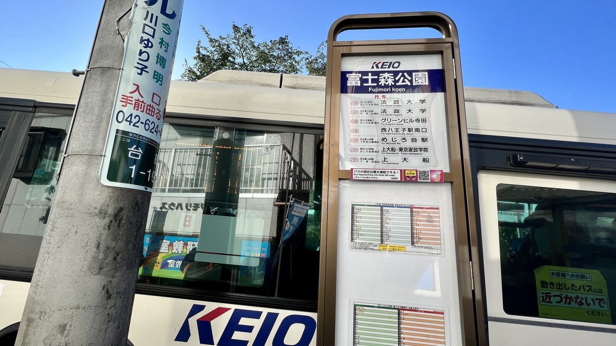 富士森公園バス停に停車するバスと乗車の準備をする人たち