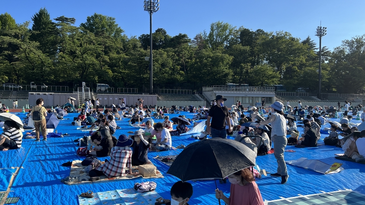 家族連れや友人同士が花火観覧の準備をしている富士森陸上競技場