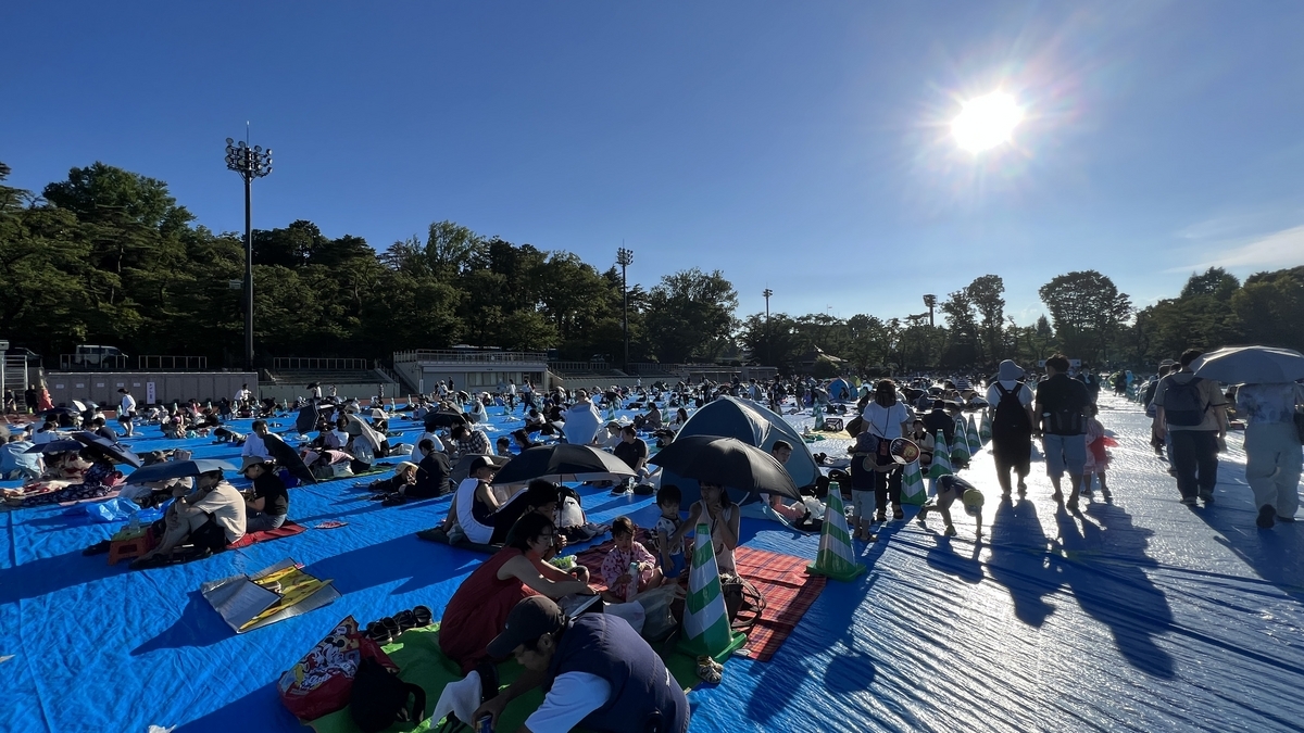 レジャーシートに座って花火の開始を待つ人たち