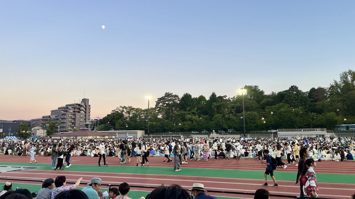 花火開始前の夕暮れ時に観覧席が埋まり始める様子