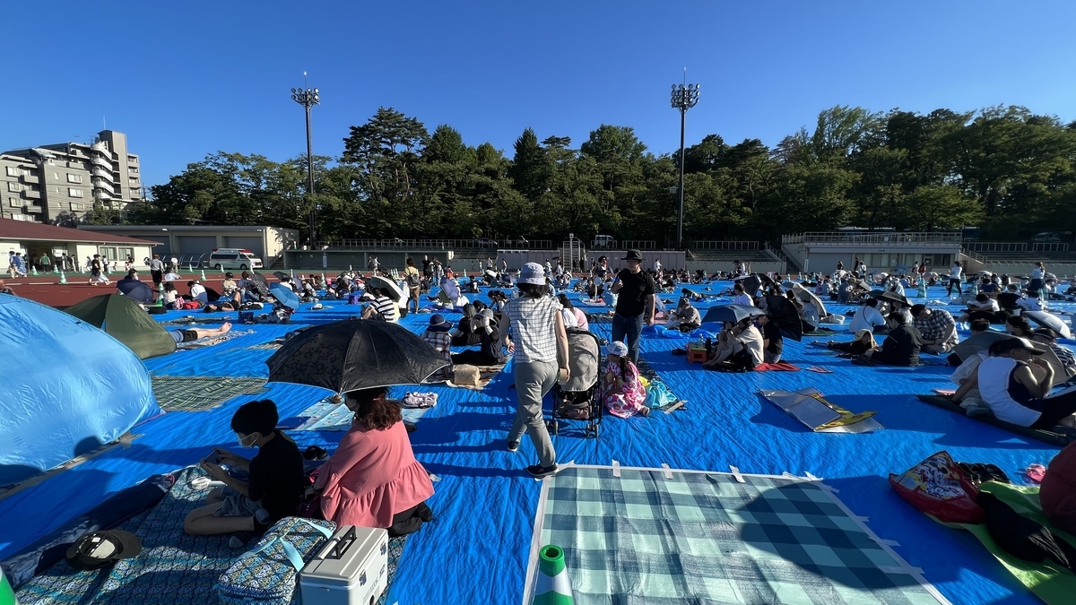 レジャーシートを広げて飲み物や食べ物を準備する観覧客