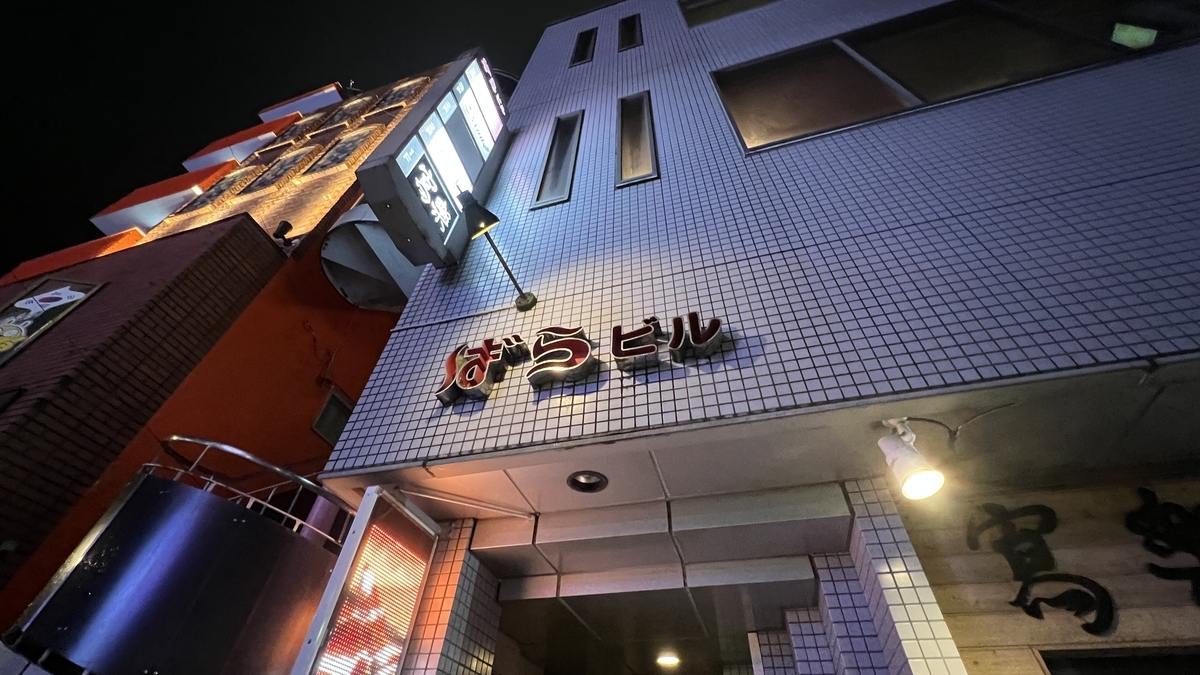 Exterior of a multi-tenant building in Nishitachi with bright signs glowing at night