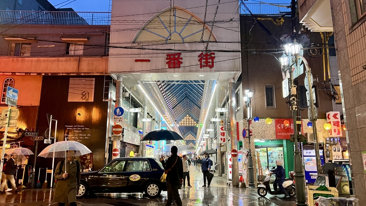 Night view of the Ichibangai arcade entrance with people walking through