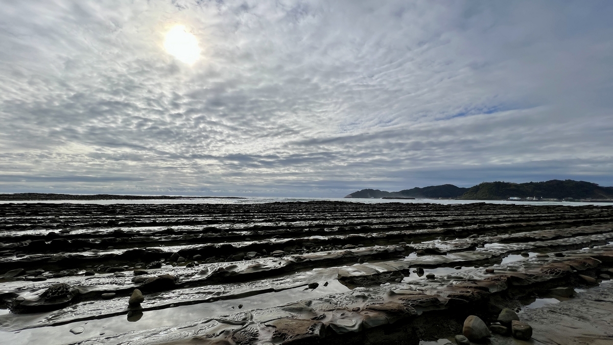 青島の海岸に続く鬼の洗濯板の広がりと海の景色 光を受けた岩の凹凸が特徴的