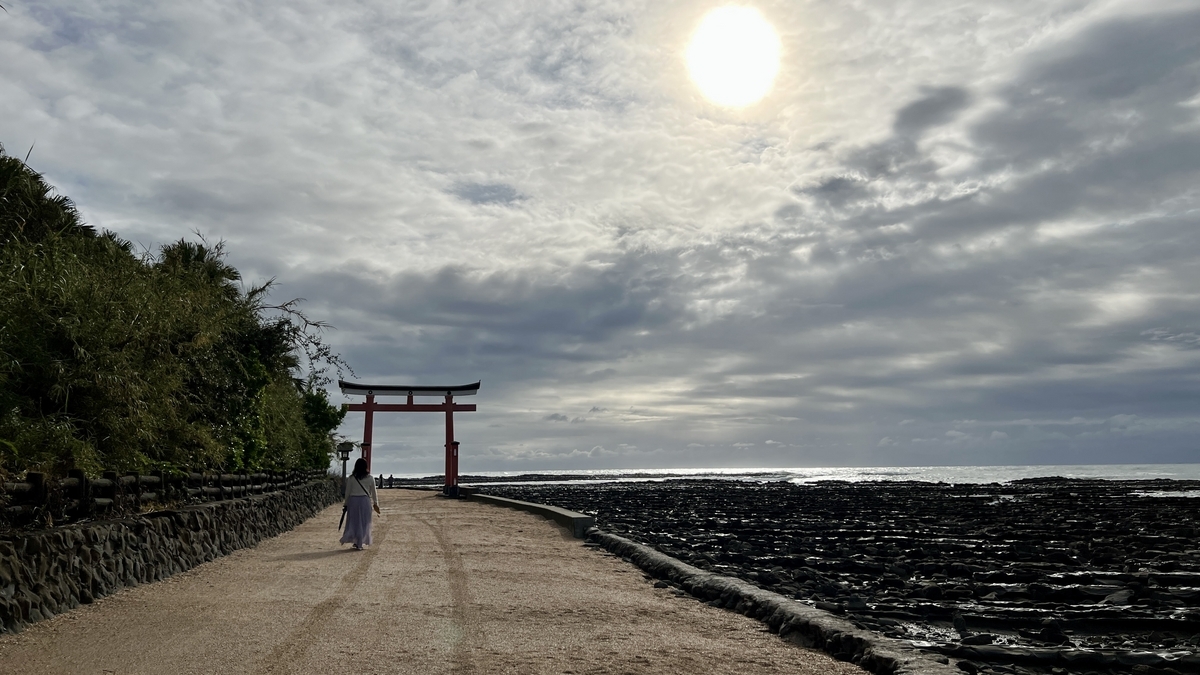 青島神社へ続く参道の先に朱色の鳥居が立つ風景 海と岩場が左右に広がる