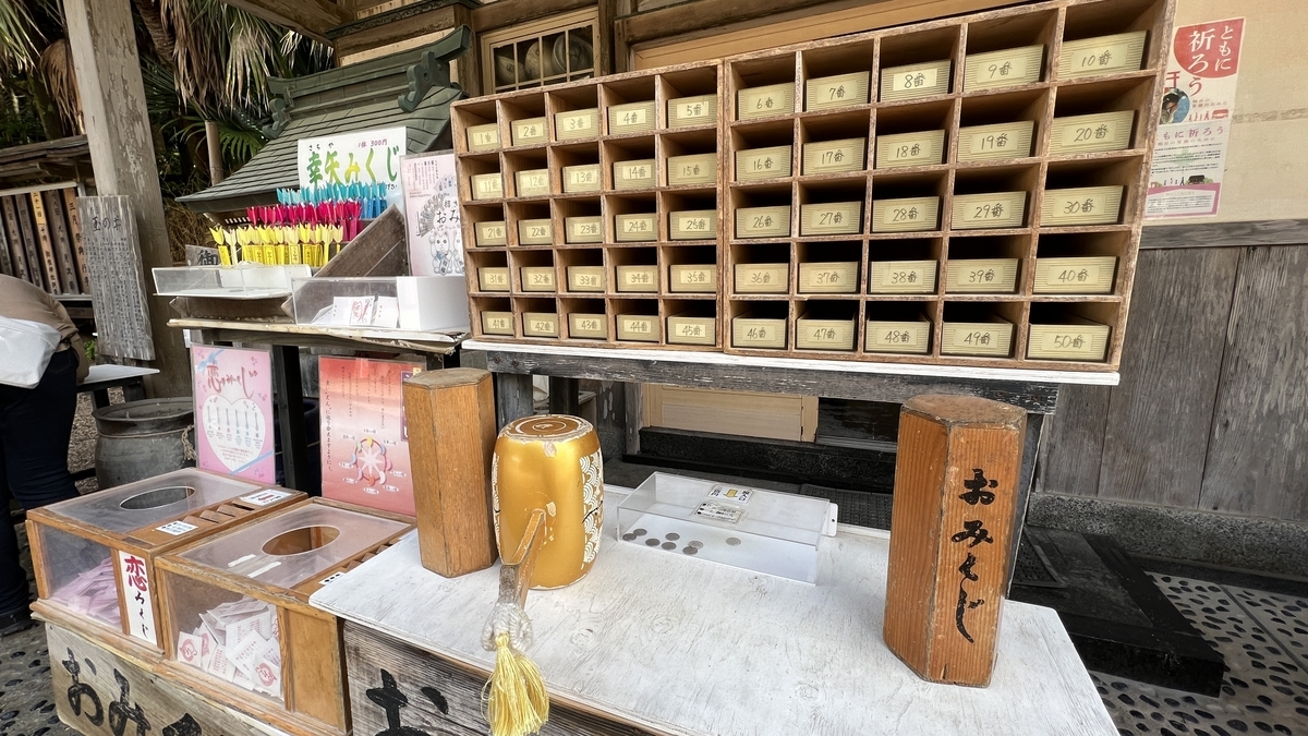 青島神社のおみくじの引き出しが並ぶ棚 数多くの木製引き出しと授与品が置かれた様子