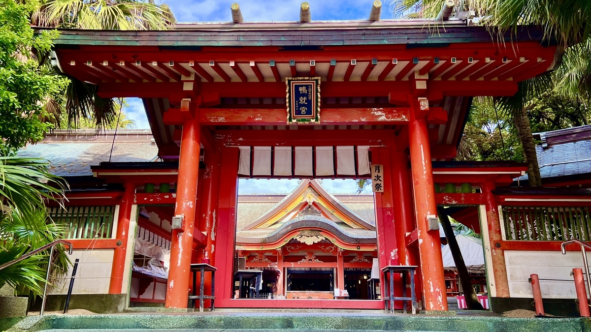 朱色の鳥居と門が連なる拝殿への入口 周囲に南国植物が茂る青島神社