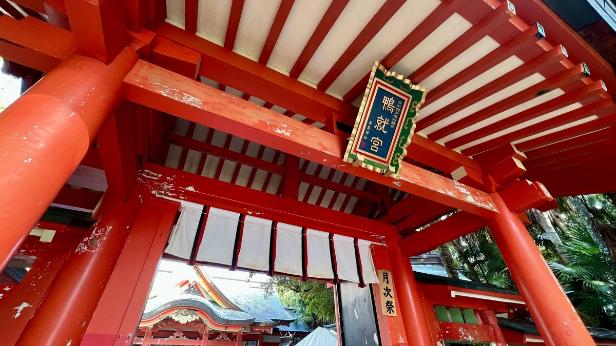 青島神社の拝殿に続く大きな朱色の門を下から見上げた様子 装飾と木組みが際立つ