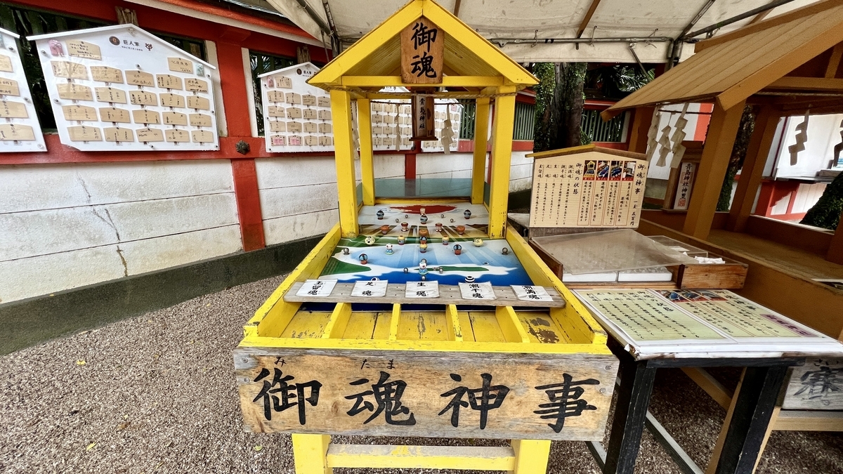 黄色い枠で囲まれた御魂神事の台が並ぶ様子 青と白が描かれた盤面と賽が置かれている