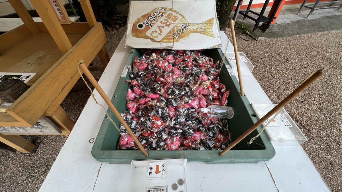 赤い鯛が多数入った水槽型の箱と釣り竿のセット 鯛みくじを釣り上げるための道具が置かれている