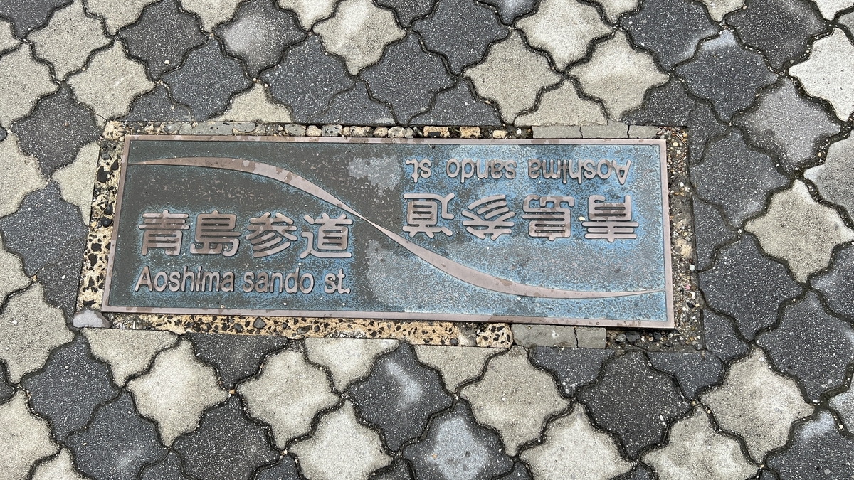 歩道に埋め込まれた青島参道商店街のプレート 青島参道の表示が刻まれている