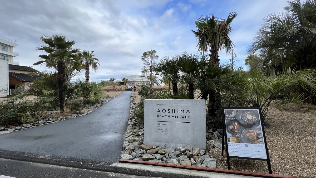 青島の海辺にある飲食施設AOSHIMA BEACH PARKの入口看板と南国植物が並ぶ風景