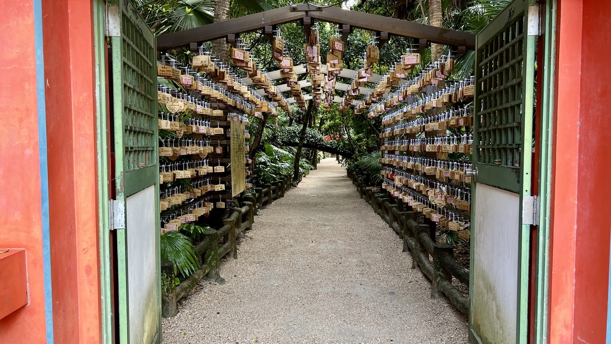 絵馬がぎっしり吊るされた祈りの古道の入口 朱色の門越しに絵馬のトンネルが続く光景